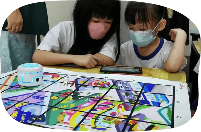 Students programming a robot on a coding mat